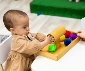 Toddler girl playing with montessori pompom wooden material practicing fine motor skills